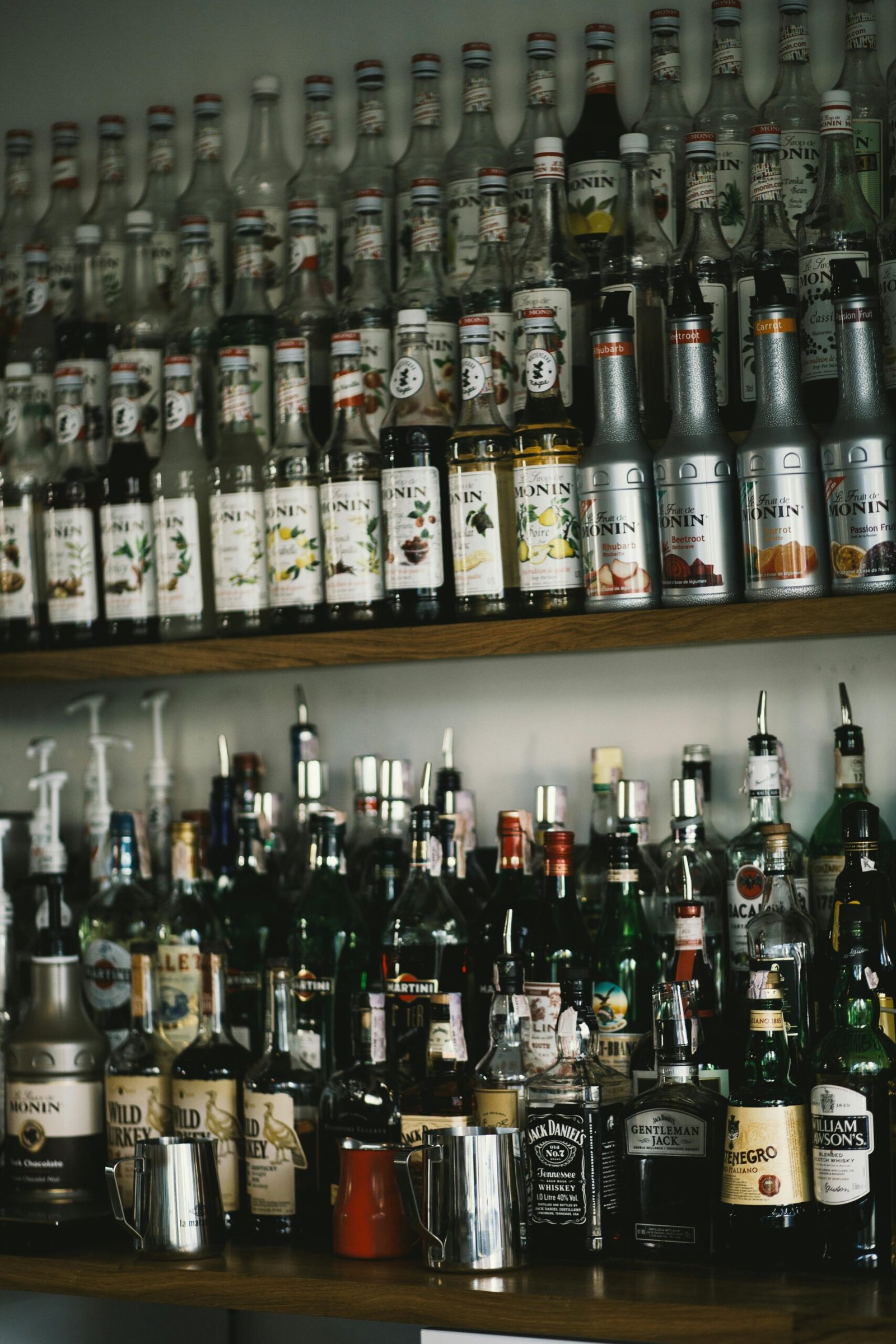 A collection of assorted liquor and syrup bottles neatly arranged on a store shelf.